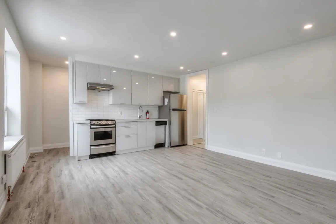 open concept kitchen with white cupboards and stainless steal appliances