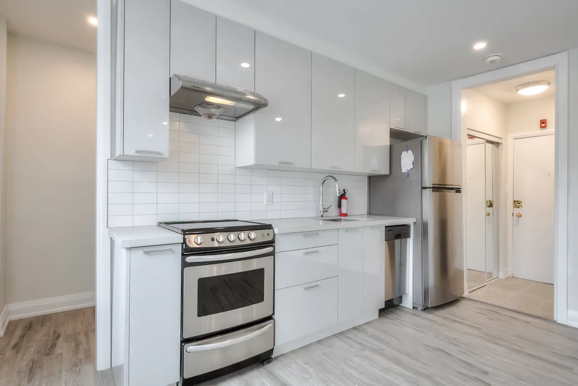 open concept kitchen with white cupboards and stainless steal appliances