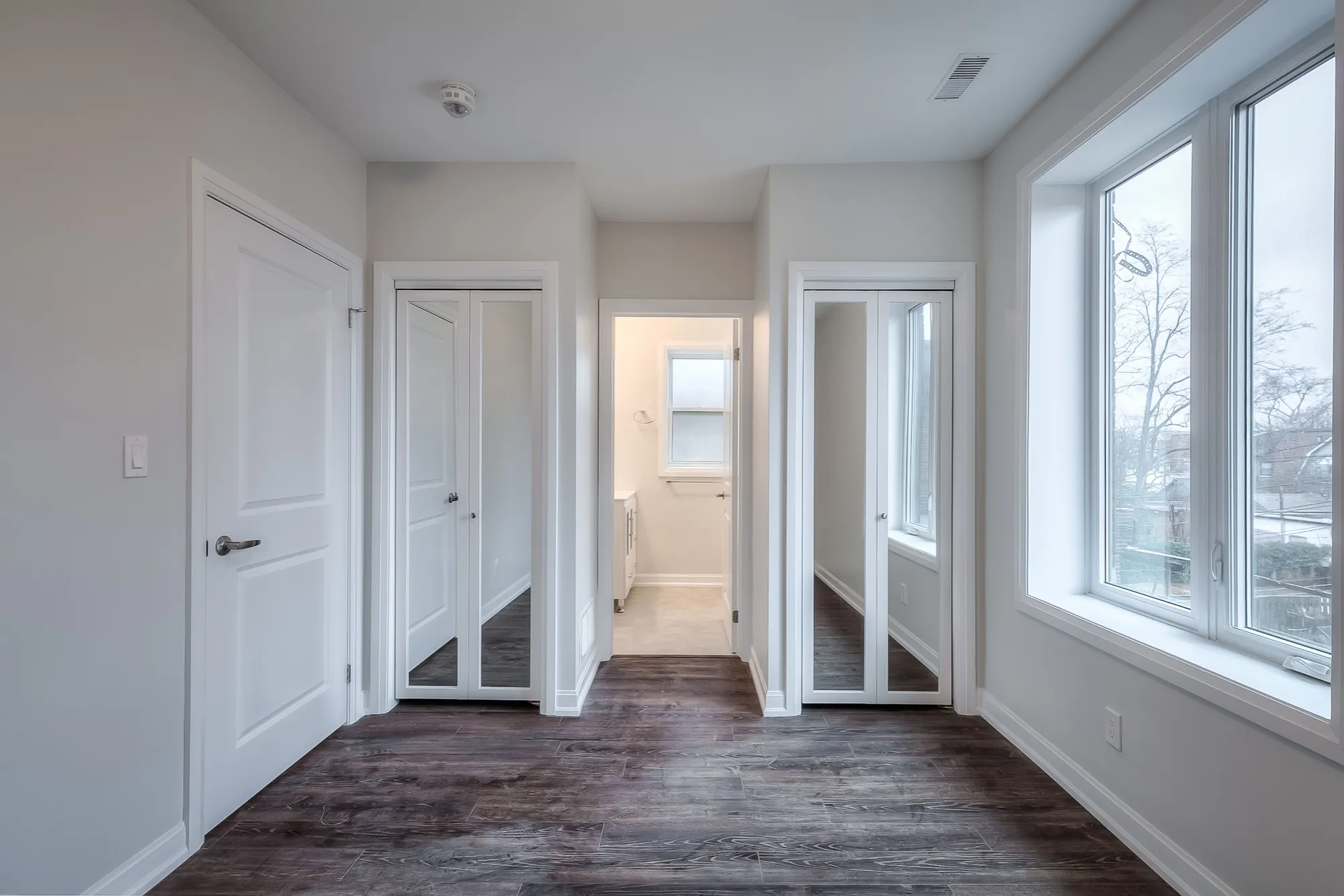 bedroom with hardwood floors, large windows and two closets