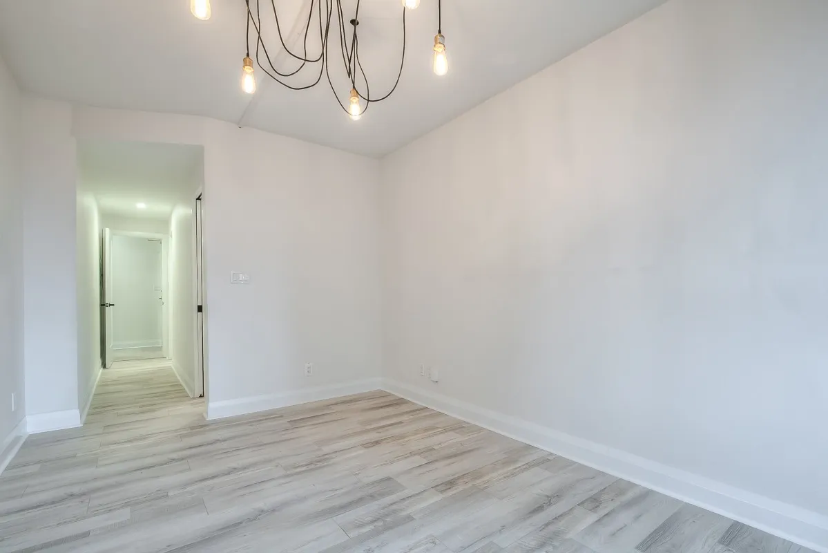 A room with a chandelier and wood floors