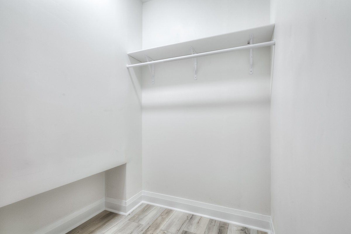 A white room with a shelf and a wood floor