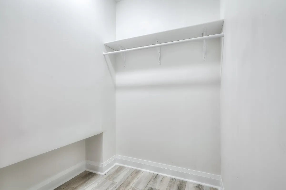 A white room with a shelf and a wood floor