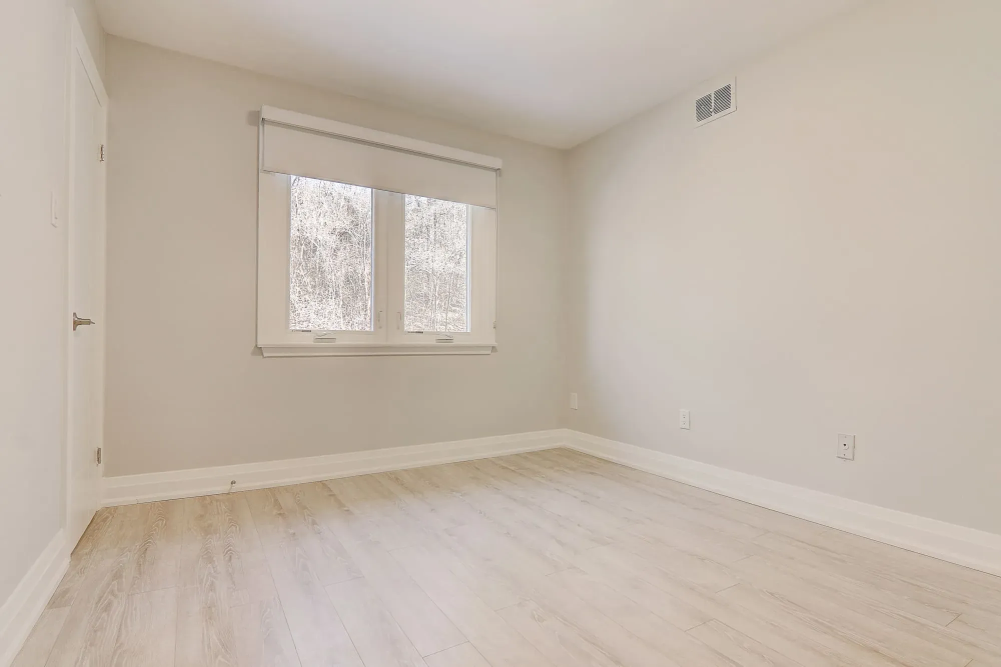 A room with a window and hardwood floor