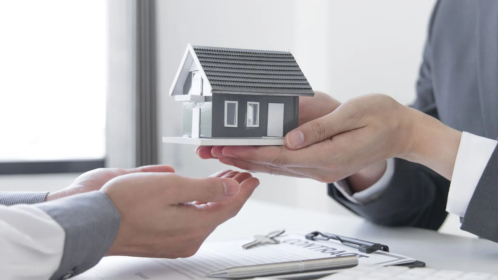 A person handing over a small house