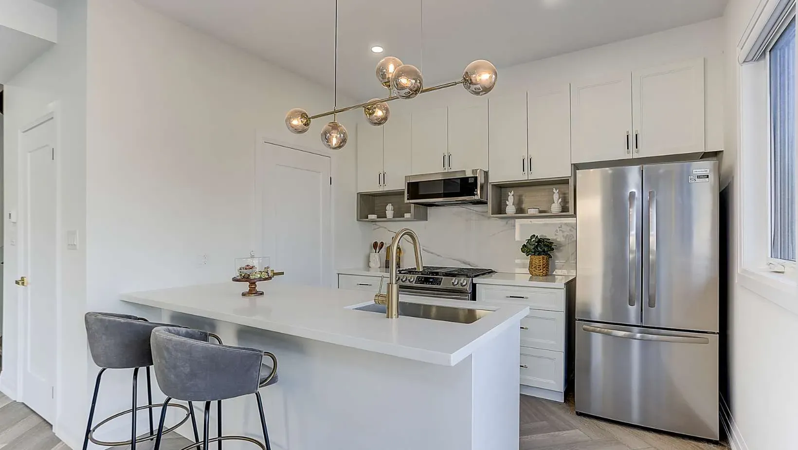 A kitchen with a white island and a stainless steel refrigerator